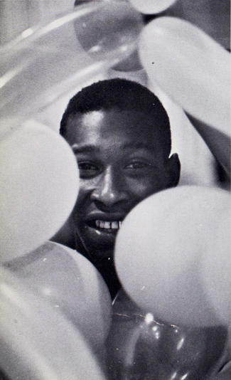 Joseph Vaughn&#039;s face peaks out from behind 5 light-colored balloons