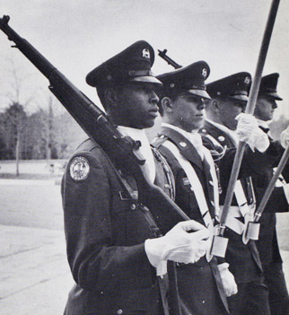Joseph Vaughn and three white students wearing uniforms and holding rifles