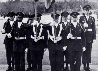 Group of men wearing dark uniforms and holding rifles.