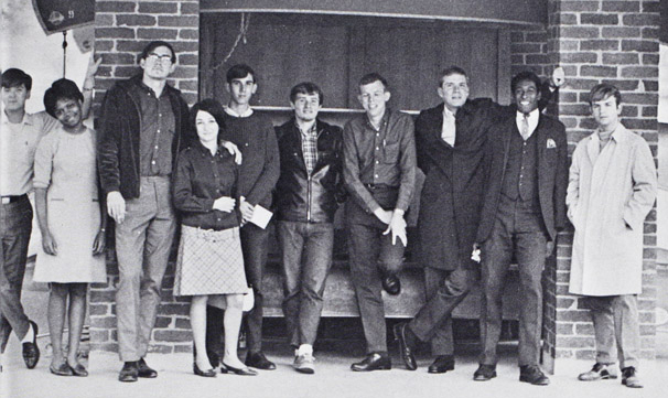 A small group of students standing in front of a window.